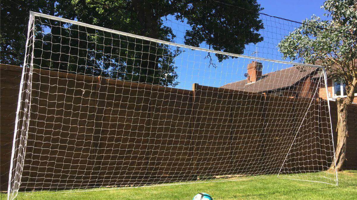 Young soccer player practicing in the backyard with an Open Goaaal 3-in-1 rebounder and goal