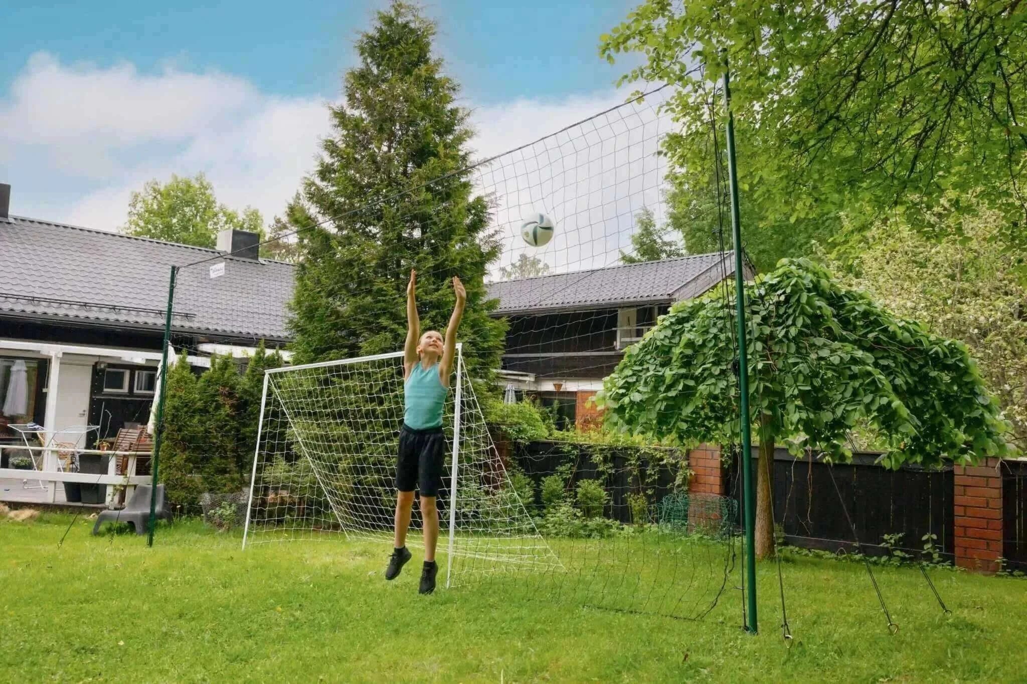 Soccer trainer in backyard with rebounder, goal, and backstop.