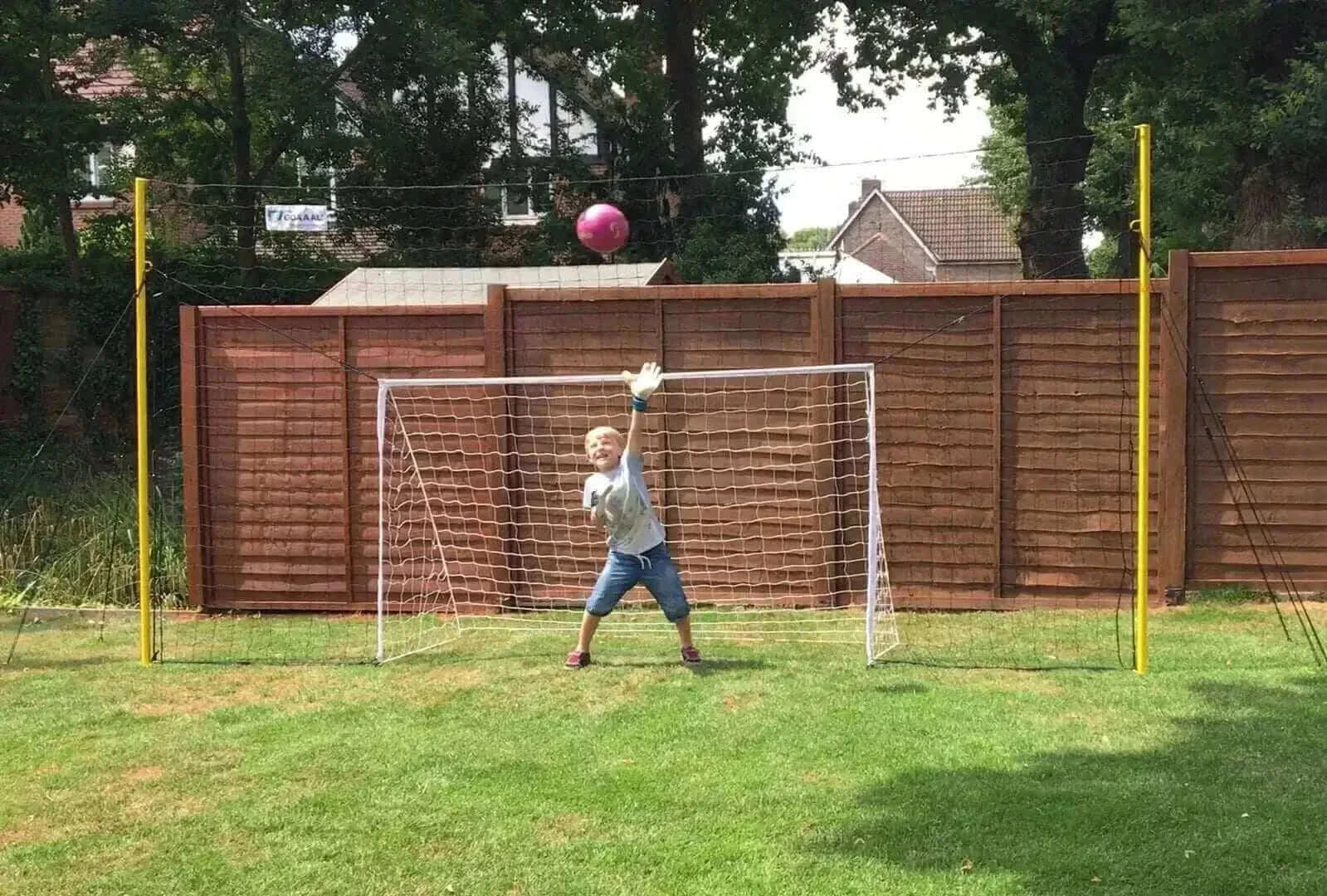 Open Goaaal® Soccer 3-in-1 Trainer for juniors set up in yard with child playing goalkeeper.