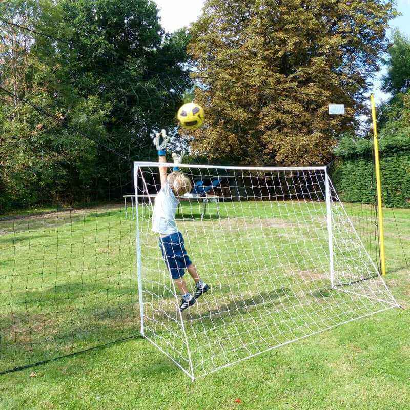 Junior soccer goal trainer with rebounder net and child goalie in backyard playing soccer