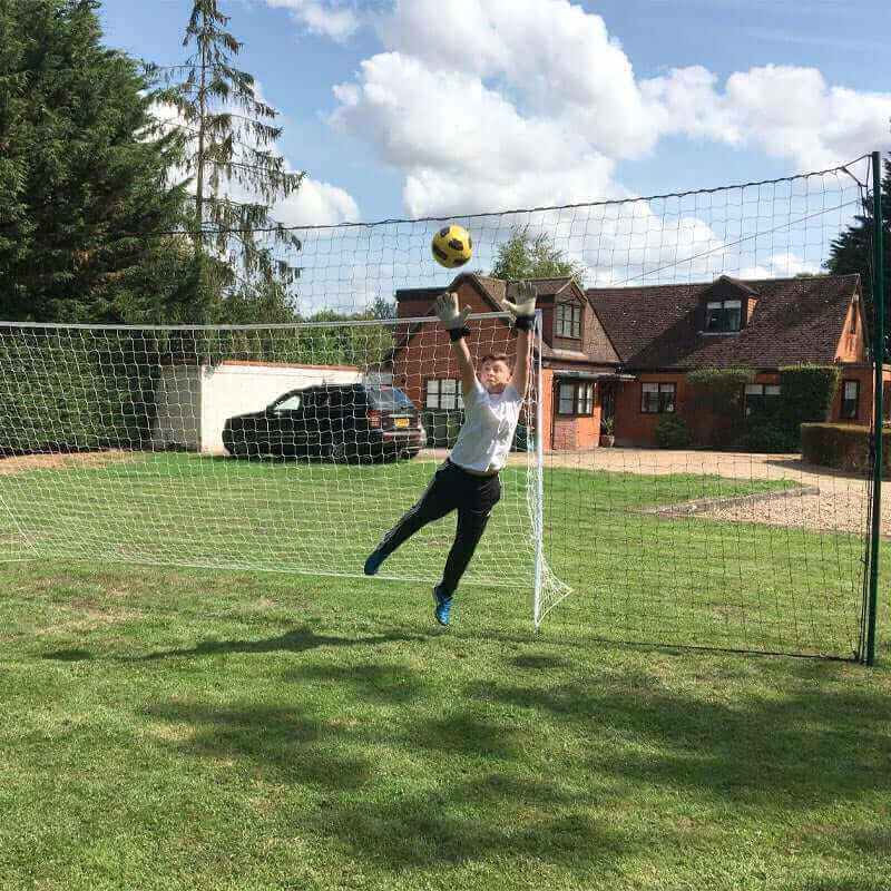 Large 3-in-1 soccer goal trainer with rebound net in backyard showing goalkeeper saving ball