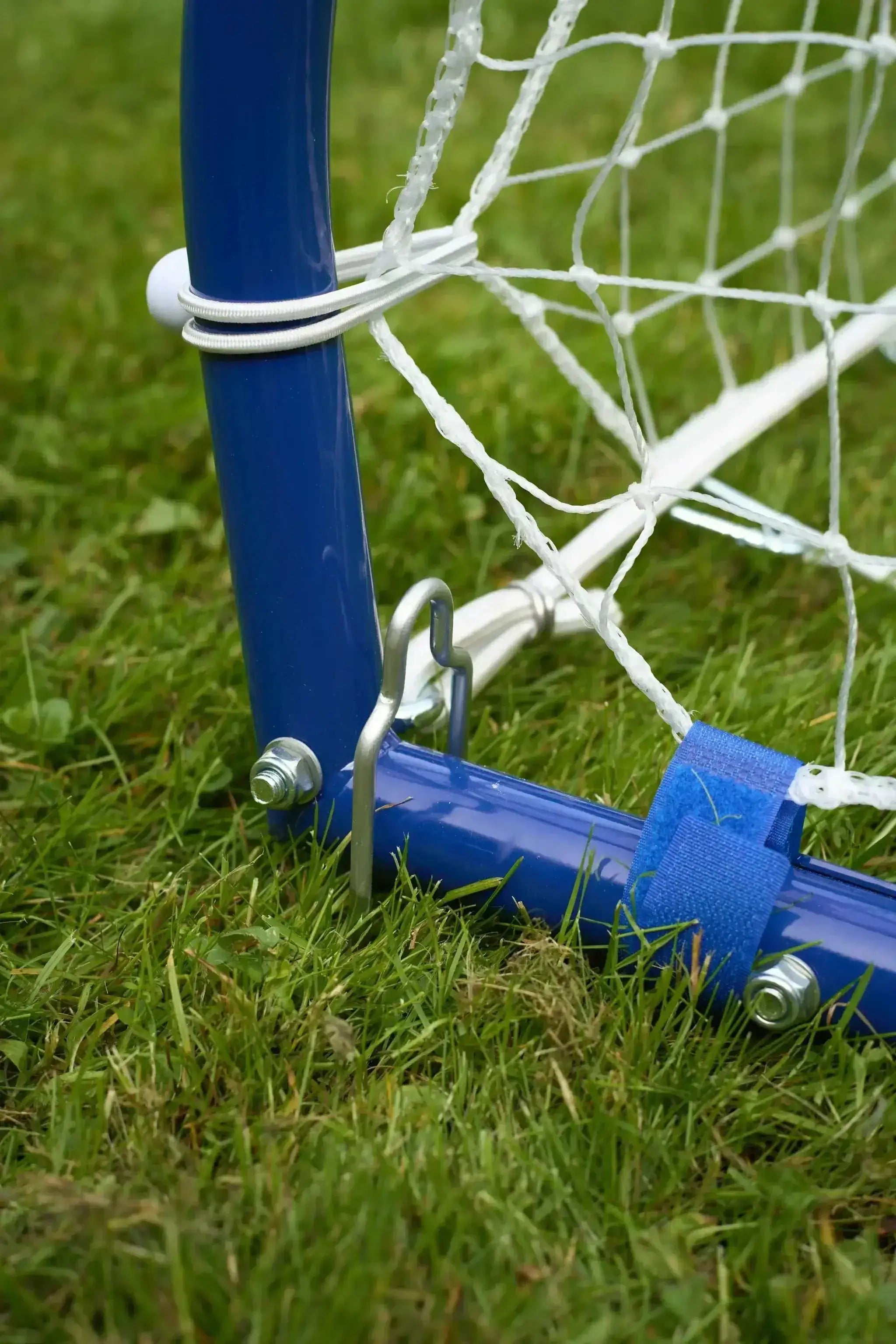 Close-up of blue 3-in-1 soccer goal rebounder frame and net on grass