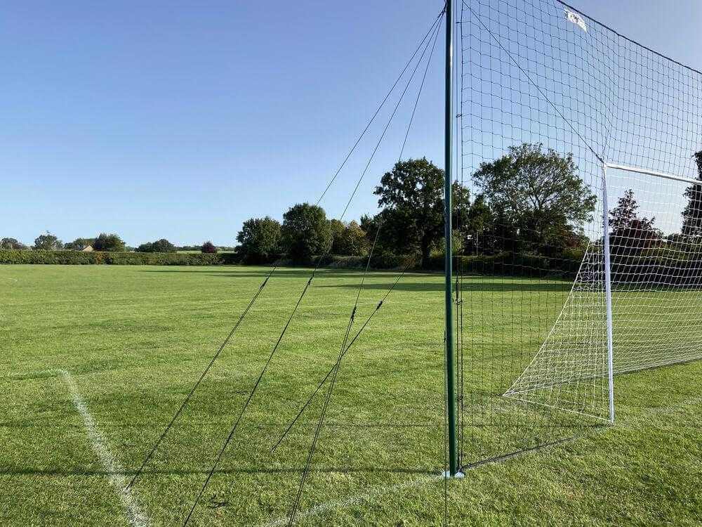 3-in-1 Soccer Goal Trainer with net on grass field, regulation-size goal, rebounder, and backstop.