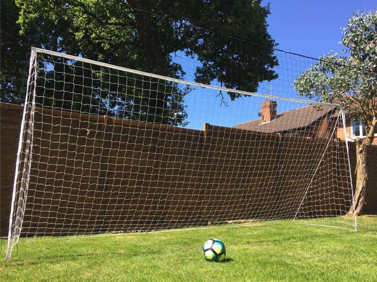 Young soccer player practicing in the backyard with an Open Goaaal 3-in-1 rebounder and goal