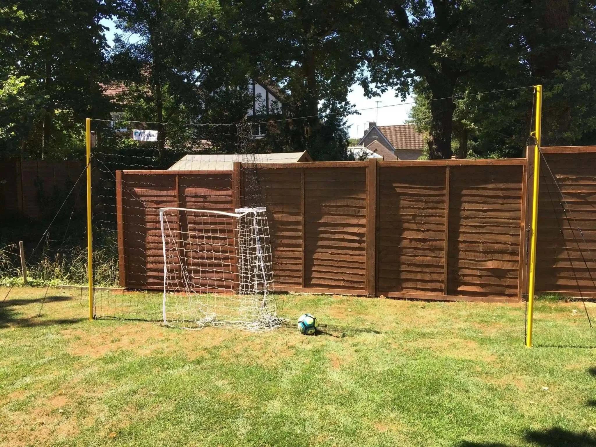 Open Goaaal® Soccer 3-in-1 Trainer in a backyard setup, featuring a goal, rebounder, and backstop.