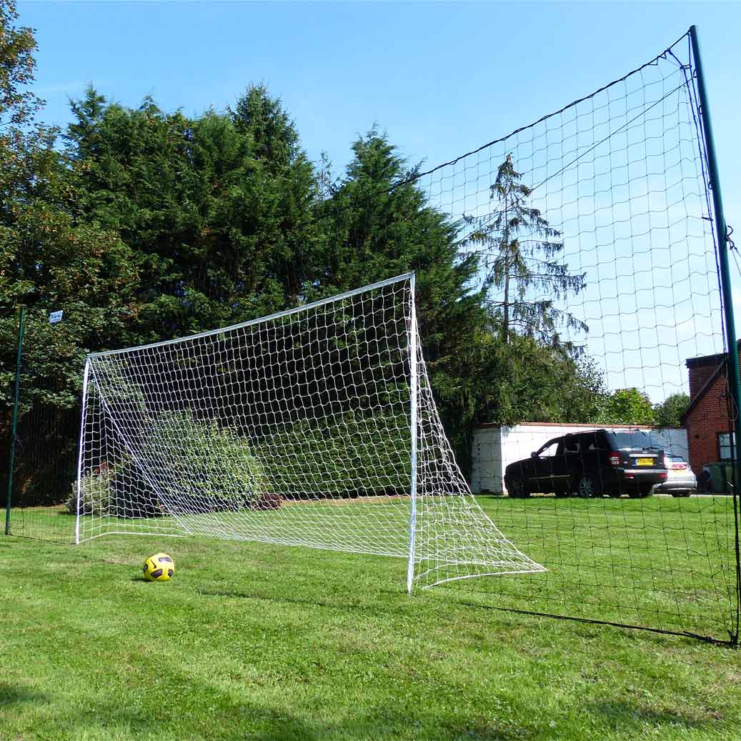Large 3-in-1 soccer goal trainer with rebounder net set up on backyard lawn
